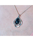 4.30 ct. teardrop Ethiopian black opal pendant in sterling silver, worn on a woman's chest.
