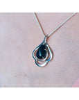 4.30 ct. teardrop Ethiopian black opal pendant in sterling silver, worn on a woman's chest.