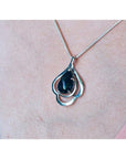 4.30 ct. teardrop Ethiopian black opal pendant in sterling silver, worn on a woman's chest.