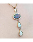 Black and white Australian opal pendant with an oval black opal, two teardrop white opals, and diamond accents on a 14K gold chain.