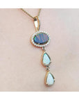 Black and white Australian opal pendant with an oval black opal, two teardrop white opals, and diamond accents on a 14K gold chain.