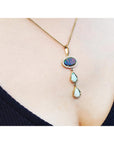 Necklace with opal pendant on a person wearing a black top.