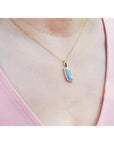 Necklace with a pendant worn by a person in a pink top