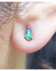 Close-up of a person wearing a teardrop-shaped opal earring.
