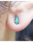 Pear-shaped Australian opal doublet stud earring with red and blue play of colors, set in 14K yellow gold.