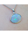 Opal pendant necklace on a person's neck with a white background