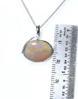 2.25 ct. Australian opal pendant in 14K white gold with bluish-green flashes, shown with a ruler.