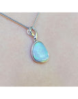 Opal pendant necklace on a person's neck against a white background