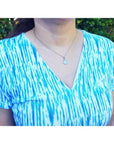 Bluish-green Australian opal pendant, freeform, bezel set in 14K white gold, worn on a silver chain.