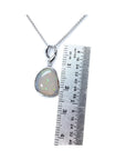 Freeform bluish-green Australian opal pendant, bezel set in 14K white gold, shown with a ruler for scale.