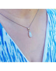 Pear-shaped white opal solitaire pendant in 14K white gold on a silver chain, worn on a person.