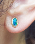 Close-up of an opal earring on a person's ear.