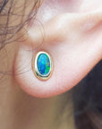 14k yellow gold oval stud earrings with sparkling blue Australian opal doublets, bezel set.