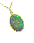 Oval Australian opal pendant with green-bluish rainbow play, set in 14K yellow gold.