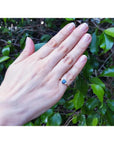 14K yellow gold ring with a vibrant oval blue sapphire and two natural diamonds on a hand.