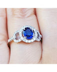 14k white gold ring with a natural blue sapphire oval cut halo diamond on a finger.