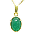 A cabochon emerald pendant on a yellow gold chain topside display.