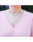 Emerald necklace with oval cut halo diamonds in 14K white gold, worn on a model.