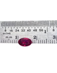 0.91 carat oval cut natural Burmese ruby with a vibrant medium deep red hue, shown next to a ruler.