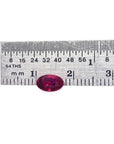 0.91 carat oval cut natural Burmese ruby with a vibrant medium deep red hue, shown next to a ruler.