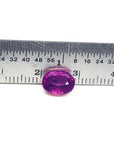 Sparkling medium rich red 2.38 carat oval cut loose natural Mozambique ruby with a ruler for scale.