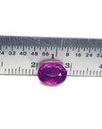 Sparkling medium rich red 2.38 carat oval cut loose natural Mozambique ruby with a ruler for scale.