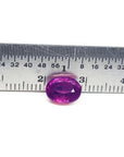 Sparkling medium rich red 2.38 carat oval cut loose natural Mozambique ruby with a ruler for scale.