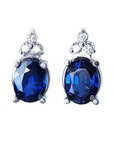 Natural blue sapphire earrings oval cut stud diamonds white gold, topped with three prong-set natural diamonds.