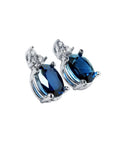 Oval natural blue sapphire stud earrings with three prong-set diamonds in 14K white gold.