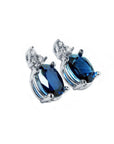 Oval natural blue sapphire stud earrings with three prong-set diamonds in 14K white gold.