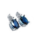 Oval natural blue sapphire stud earrings with three prong-set diamonds in 14K white gold.