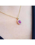 Oval pink sapphire halo diamond pendant necklace in 14K yellow gold.