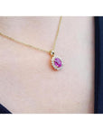 Oval pink sapphire halo diamond pendant necklace in 14K yellow gold.