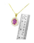Gold necklace with a pink oval cut sapphire gemstone pendant next to a ruler for scale on a white background