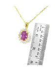 14K yellow gold necklace with oval pink sapphire halo diamond pendant, next to a ruler.