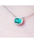 1.00 ct. oval emerald necklace with diamond halo, 14K white gold chain on skin.