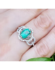1.55 ct. oval emerald clover ring with diamond halo in 14K white gold on a hand.
