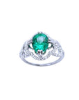 An oval cut Colombian emerald in the center of a clover ring design adorned with natural diamonds.