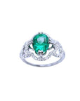 An oval cut Colombian emerald in the center of a clover ring design adorned with natural diamonds.