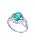 A detailed view of an oval cut emerald centered in a clover ring design adorned with diamonds.