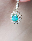 Close-up of a gold earring USA made Colombian emeralds on a person's ear.