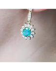 Close-up of a gold earring USA made Colombian emeralds on a person's ear.