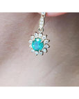 Close-up of a gold earring USA made Colombian emeralds on a person's ear.