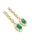 A pair of a 14k yellow gold with natural colombian emerald earrings with a halo diamond.