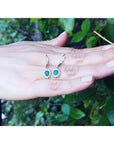 1.09 carat oval cut Colombian emerald and diamond halo earrings in 14K gold with lever backs.