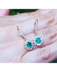 1.09 carat oval cut emerald earrings with diamond halo, 14K gold lever backs.
