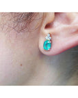 Close-up of an ear wearing a diamond and emerald earring.