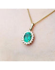 18k gold necklace with an oval cut natural emerald necklace pendant in a halo diamond.