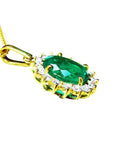 Oval natural emerald pendant with halo diamonds in 18K yellow gold.