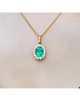 Oval 3.01 ct natural emerald pendant with halo diamonds on an 18K yellow gold chain.
